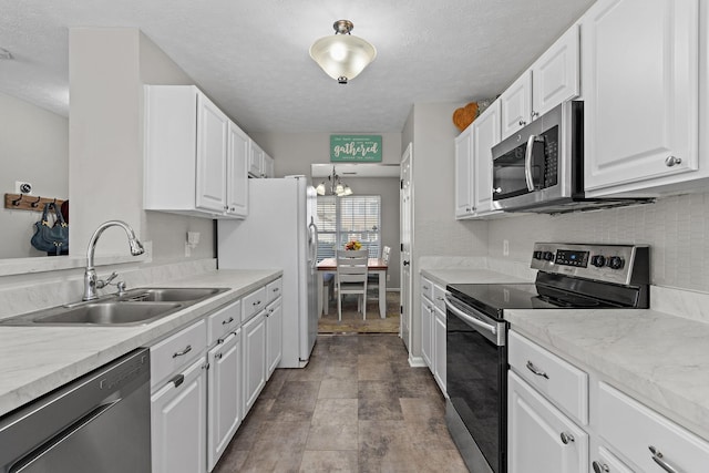 kitchen with tasteful backsplash, light countertops, appliances with stainless steel finishes, white cabinetry, and a sink