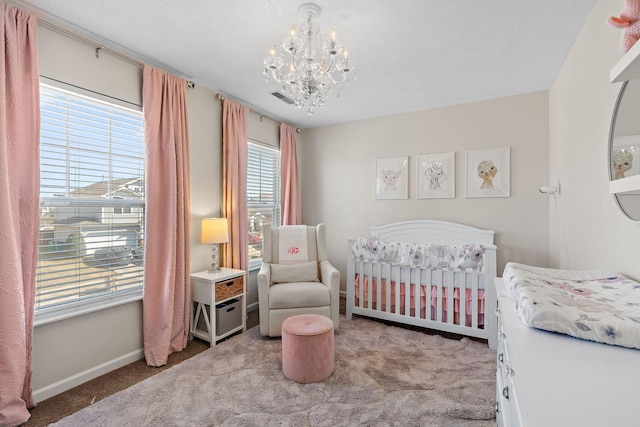 bedroom with carpet floors, visible vents, a chandelier, a nursery area, and baseboards