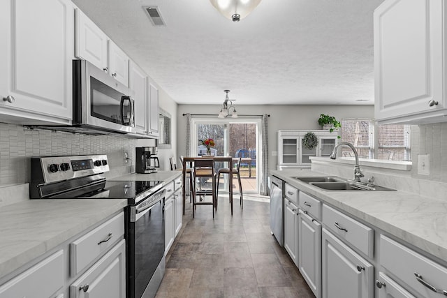 kitchen with stainless steel appliances, visible vents, white cabinets, a sink, and a healthy amount of sunlight