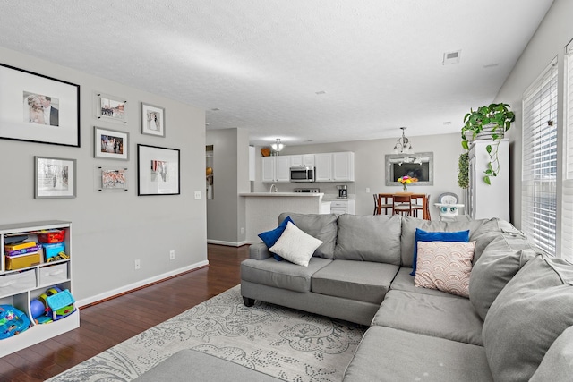 living area with visible vents, a textured ceiling, baseboards, and dark wood-style flooring