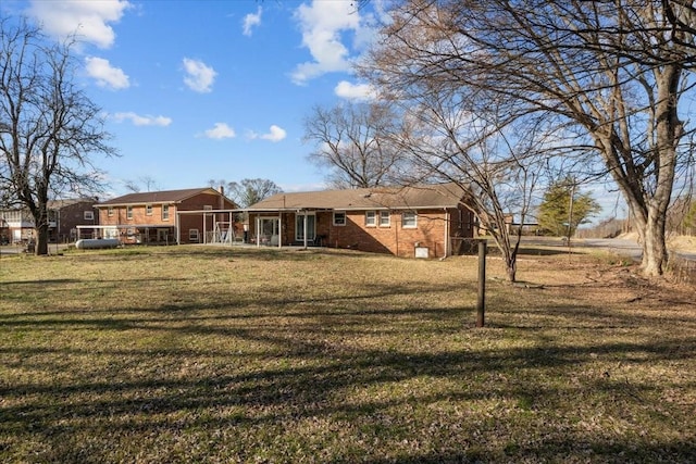 rear view of house featuring brick siding and a yard