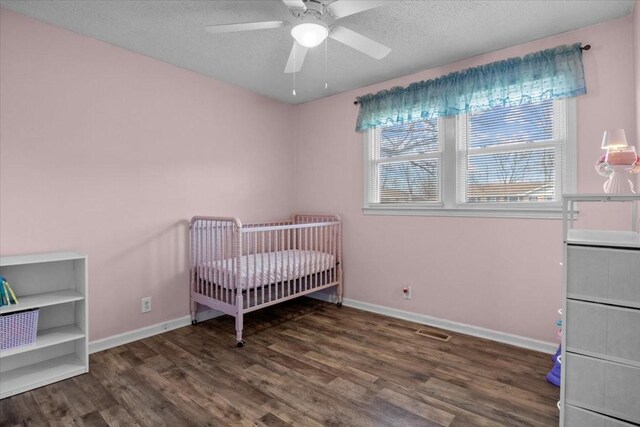 bedroom featuring visible vents, a textured ceiling, baseboards, and wood finished floors