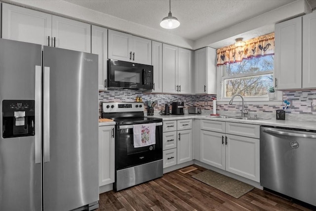 kitchen with dark wood-style flooring, tasteful backsplash, light countertops, appliances with stainless steel finishes, and a sink