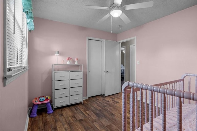 bedroom with a textured ceiling, ceiling fan, wood finished floors, a closet, and a crib