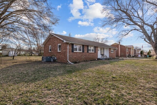 view of front of property with cooling unit, brick siding, a front lawn, and entry steps