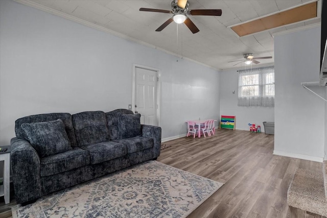 living room with ornamental molding, a ceiling fan, baseboards, and wood finished floors