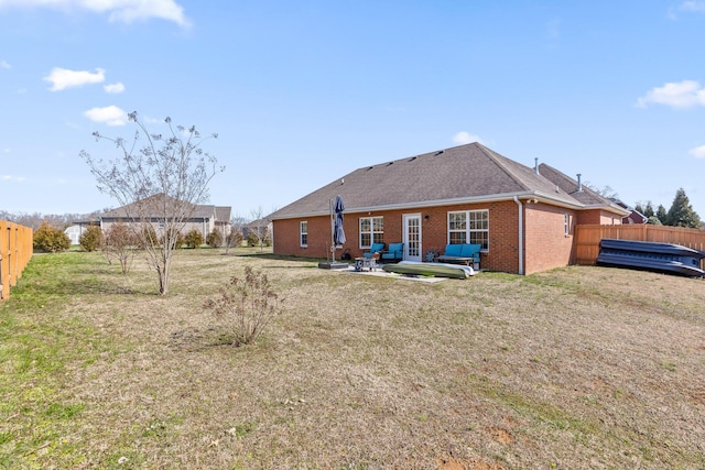 rear view of house featuring brick siding, a fenced backyard, a yard, and a patio