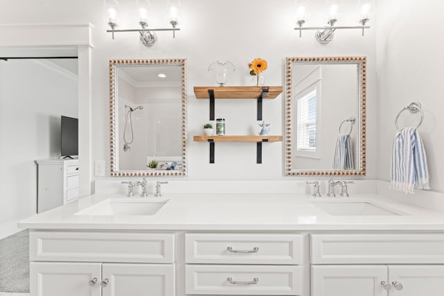 bathroom featuring double vanity, crown molding, a shower, and a sink