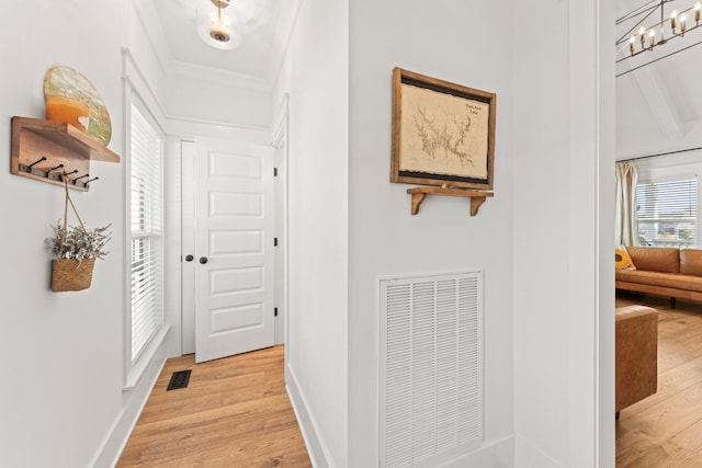 corridor with light wood-type flooring, visible vents, and baseboards