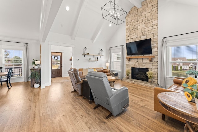 living area featuring high vaulted ceiling, a stone fireplace, a healthy amount of sunlight, and light wood-style floors