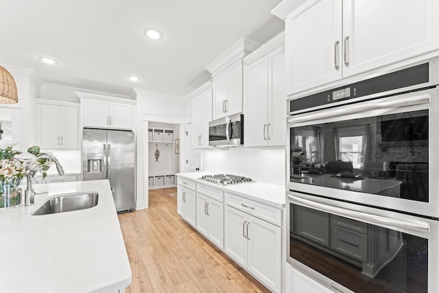 kitchen featuring tasteful backsplash, light countertops, appliances with stainless steel finishes, white cabinetry, and a sink