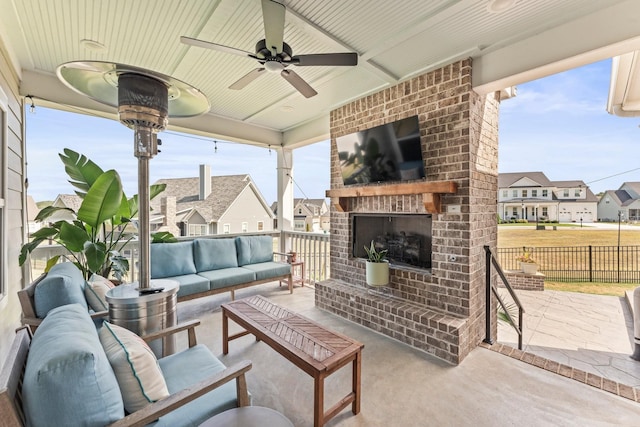 view of patio featuring ceiling fan, an outdoor living space with a fireplace, fence, and a residential view