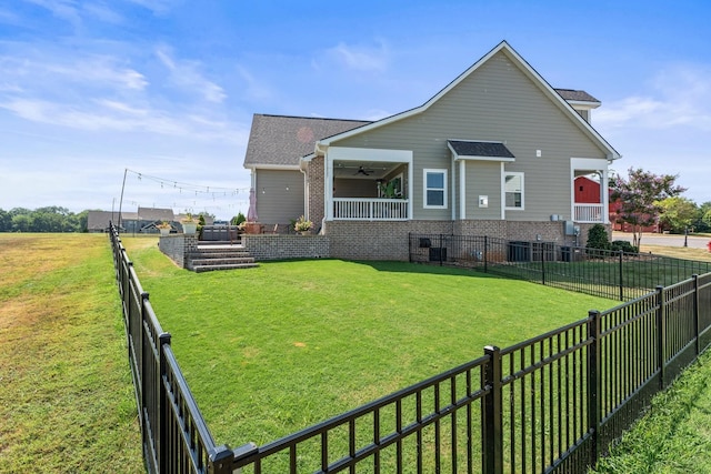 rear view of house with a yard, brick siding, a fenced backyard, and a ceiling fan