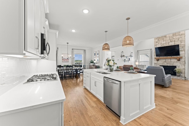 kitchen featuring light wood finished floors, light countertops, appliances with stainless steel finishes, white cabinets, and a sink