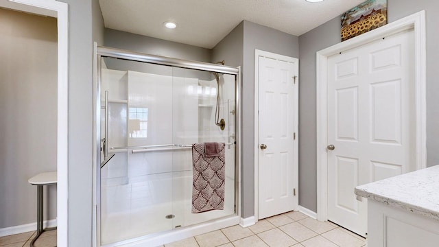 full bathroom with a stall shower, tile patterned flooring, baseboards, and vanity