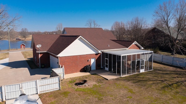 back of property featuring brick siding, fence, a sunroom, a yard, and a patio area