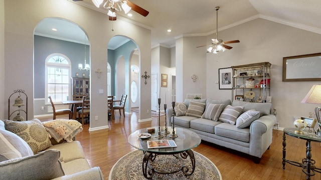 living room with crown molding, baseboards, arched walkways, and light wood-style floors