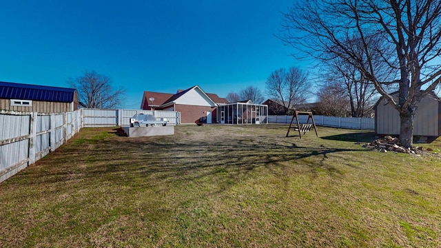 view of yard with a sunroom, a fenced backyard, a shed, and an outbuilding