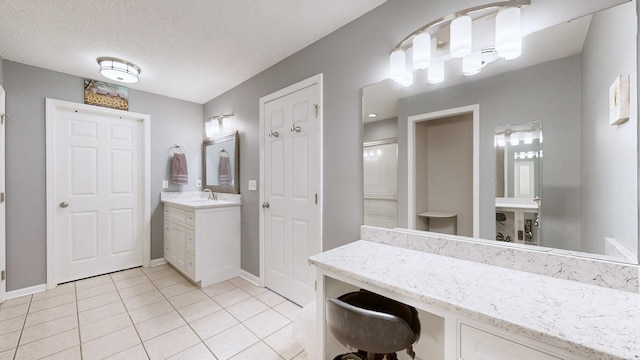 bathroom with a textured ceiling, tile patterned flooring, vanity, and baseboards