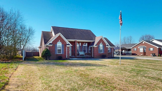 view of front facade with brick siding, a front lawn, and fence