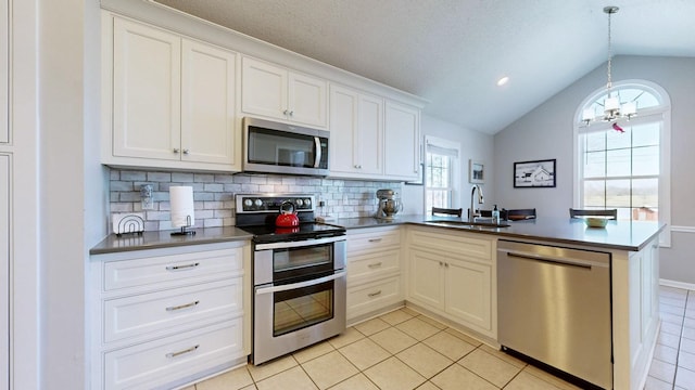 kitchen with tasteful backsplash, lofted ceiling, appliances with stainless steel finishes, a sink, and a peninsula