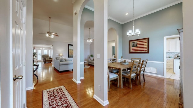 dining area featuring ceiling fan with notable chandelier, high vaulted ceiling, wood finished floors, and baseboards