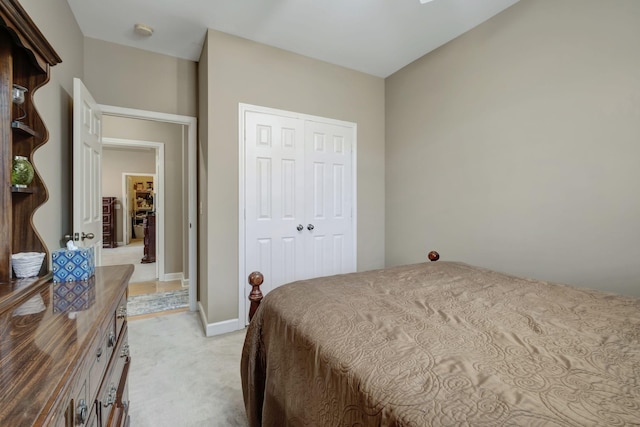 bedroom with baseboards, a closet, and light colored carpet