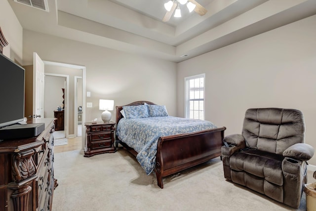 bedroom featuring ceiling fan, visible vents, a raised ceiling, and light colored carpet