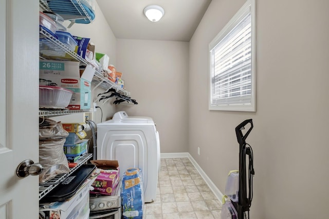 washroom featuring washing machine and dryer, laundry area, and baseboards