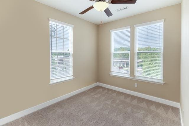 empty room featuring light carpet, visible vents, and baseboards