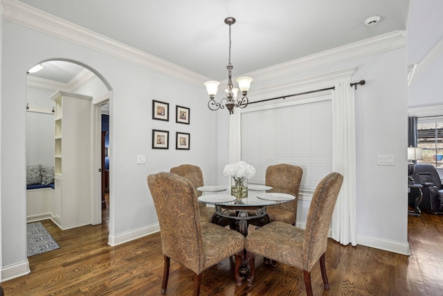 dining room with baseboards, arched walkways, dark wood finished floors, crown molding, and a chandelier