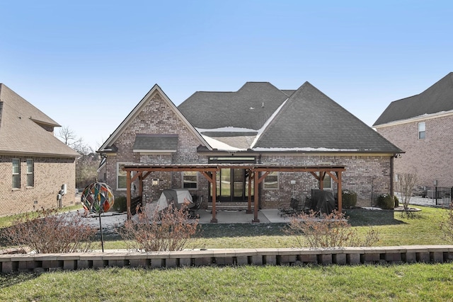 rear view of property featuring a yard, roof with shingles, a patio, and brick siding