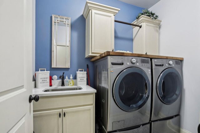 clothes washing area with a sink, washing machine and dryer, and cabinet space