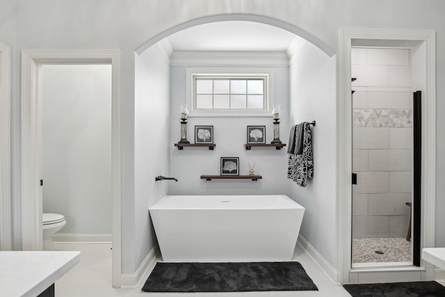 full bath featuring baseboards, a freestanding bath, a shower stall, and toilet