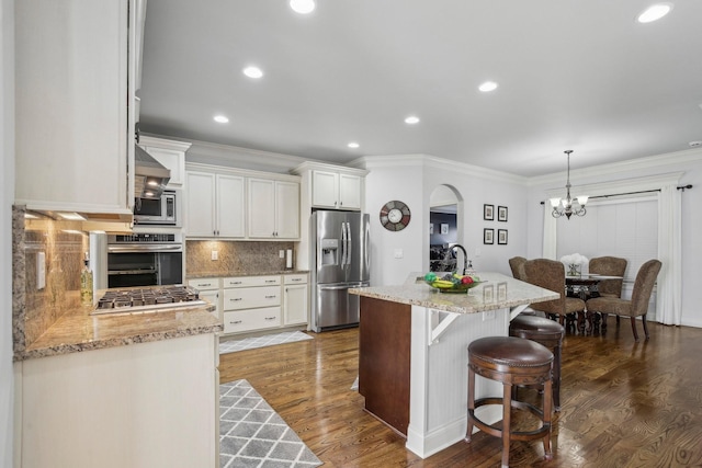 kitchen featuring tasteful backsplash, arched walkways, appliances with stainless steel finishes, dark wood-type flooring, and crown molding