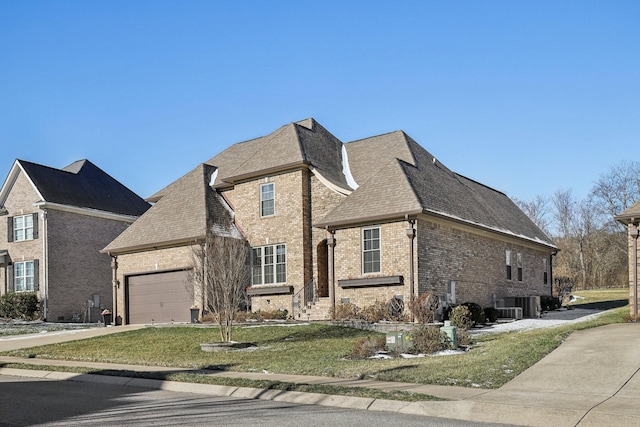 view of front of property with concrete driveway, brick siding, central AC, and an attached garage