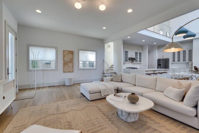 living area featuring recessed lighting, baseboards, stairway, and light wood finished floors