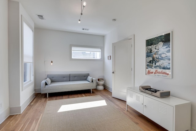 living area featuring baseboards, visible vents, and light wood-style floors