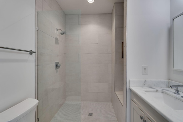 full bathroom featuring tiled shower, vanity, and toilet