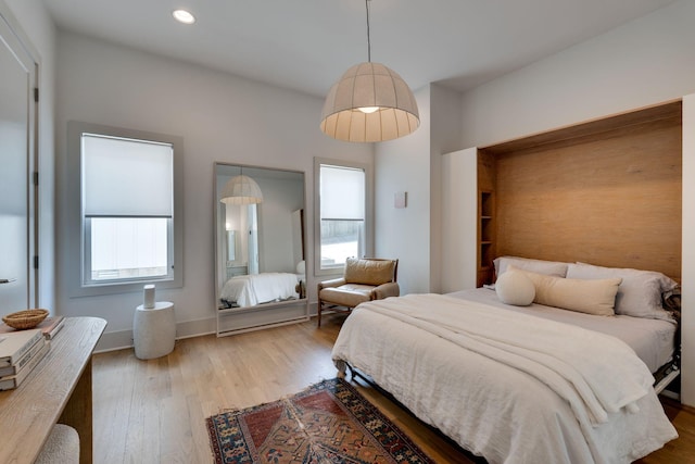 bedroom featuring baseboards, multiple windows, wood finished floors, and recessed lighting