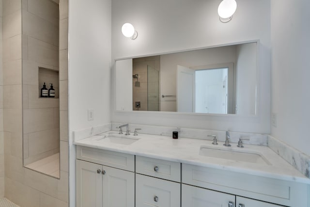 full bathroom featuring double vanity, a sink, and tiled shower