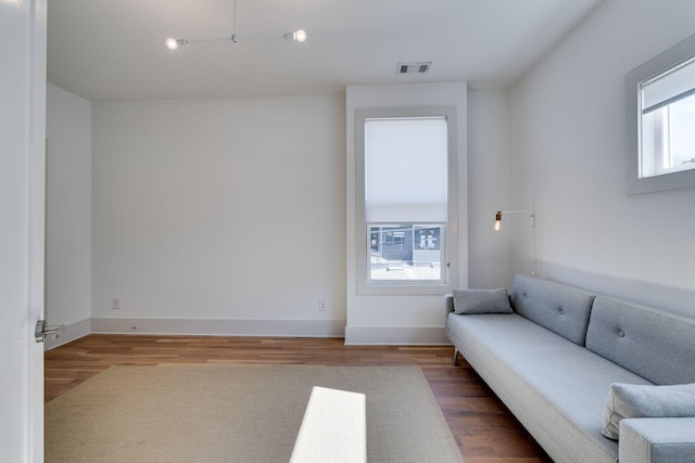 unfurnished living room featuring baseboards, visible vents, and wood finished floors