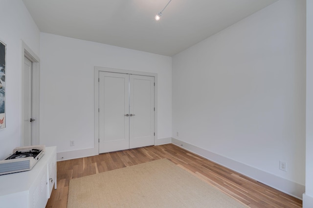 unfurnished bedroom with light wood-style floors, a closet, and baseboards