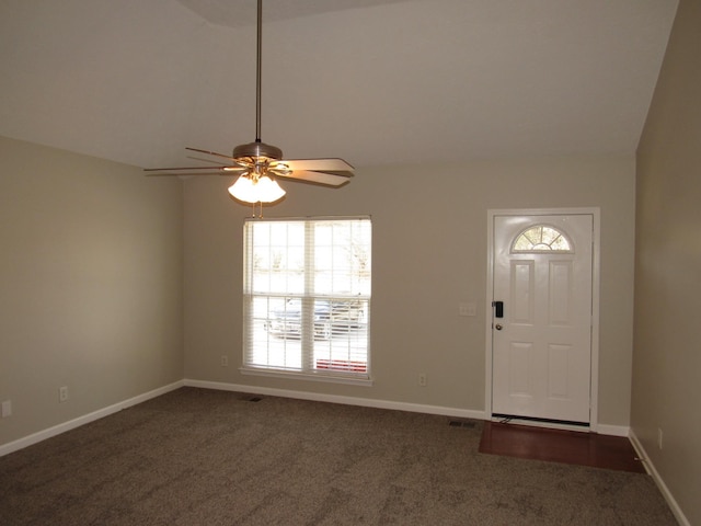 foyer entrance with a ceiling fan, vaulted ceiling, dark carpet, and baseboards