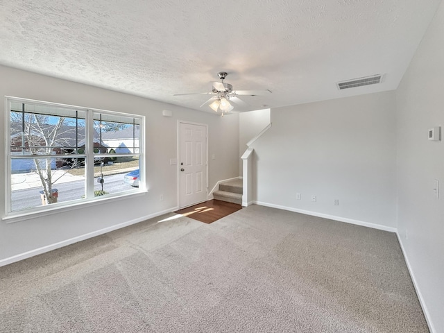 foyer with visible vents, dark carpet, stairway, and baseboards