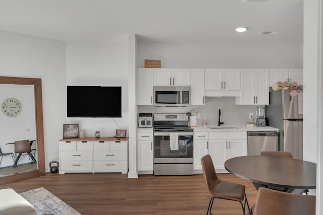 kitchen with stainless steel appliances, light countertops, decorative backsplash, white cabinets, and a sink