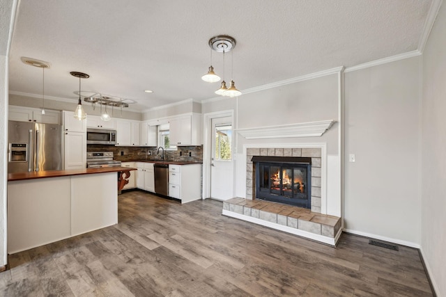 kitchen with stainless steel appliances, a sink, white cabinetry, visible vents, and crown molding