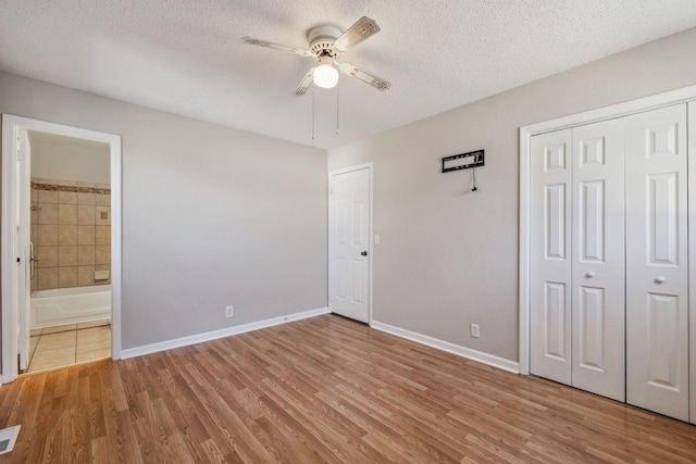 unfurnished bedroom featuring a textured ceiling, baseboards, and wood finished floors