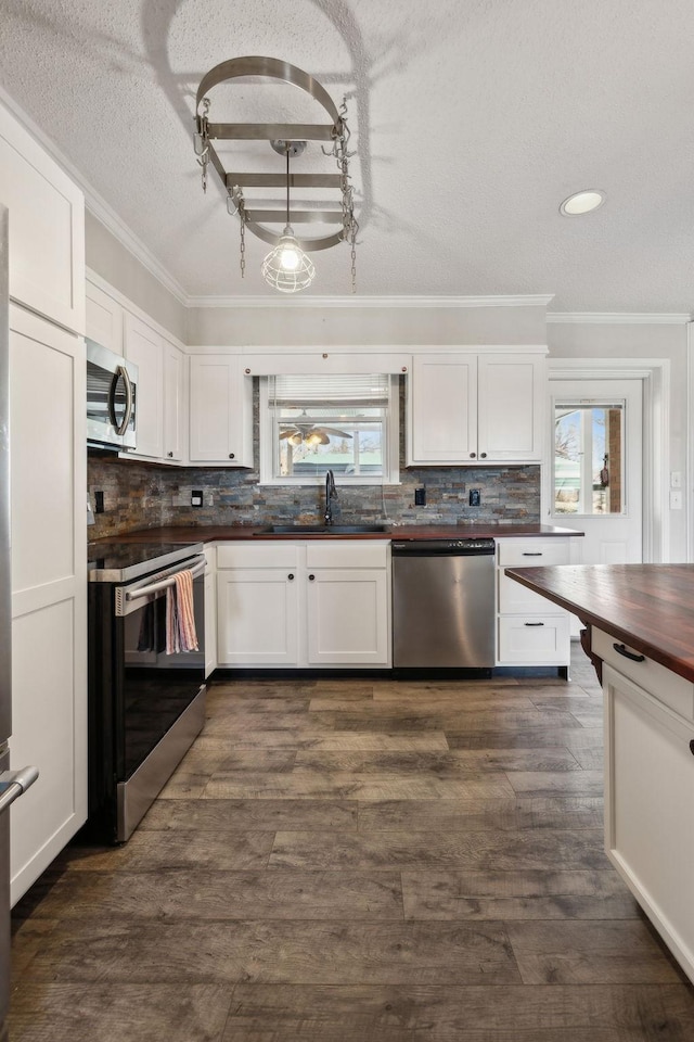 kitchen with white cabinets, ornamental molding, stainless steel appliances, and decorative backsplash