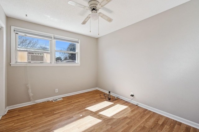 spare room featuring ceiling fan, a textured ceiling, baseboards, and wood finished floors